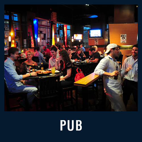People socializing and eating at a lively indoor pub with warm lighting, labeled “PUB” in bold white