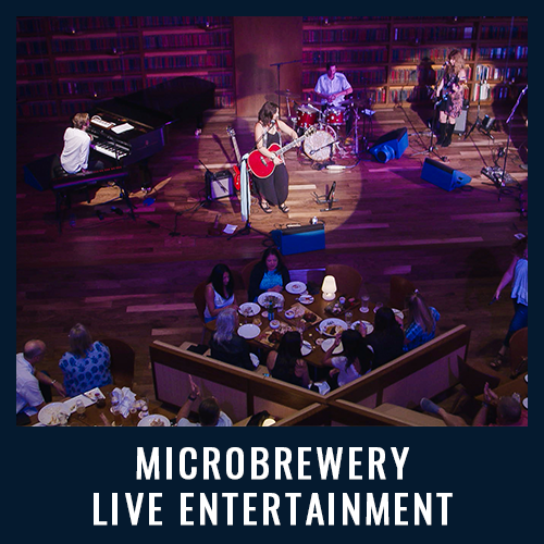 Live band performs on stage at a microbrewery while guests dine at tables