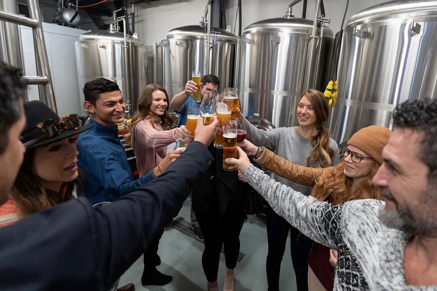 Group of people toasting with beer inside a brewery