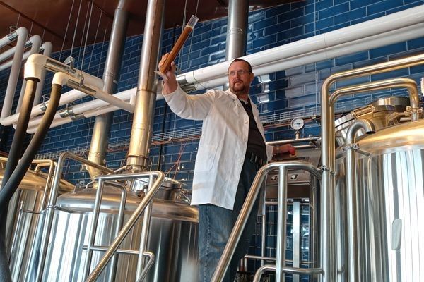 Brewer in a lab coat inspecting a beer sample with a hydrometer